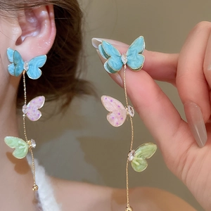 Detail view of long butterfly tassel earrings with colorful enamel and zircon crystals
