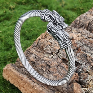 Detailed view of silver viking wolf head open bracelet with twisted rope texture on bark