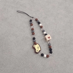 Detail of beaded phone strap with brown heart beads and cute toast charm accessory