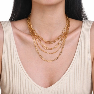 Detail of layered gold-tone square frame necklace worn on model for stylish layering