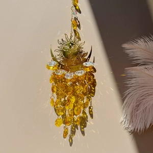 Macro shot of sun and moon crystal suncatcher reflecting light on a beige wall