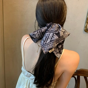 Foulard cheveux à imprimé paisley noir et blanc noué en grand nœud sur queue de cheval