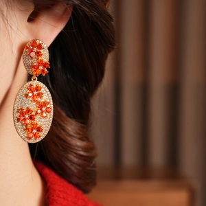 Detail of vintage flower drop earrings with orange zircon in gold-tone setting