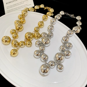 Macro shot of metallic sphere tassels and high-gloss beads on a gold and silver necklace