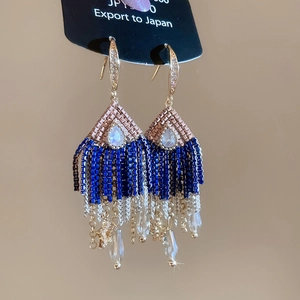 Detail of drop tassel earrings with blue beads and gold star pendants in vintage style