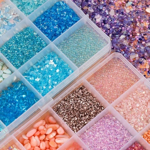 Macro view of 12-grid box with assorted colorful glass beads and nail art sequins