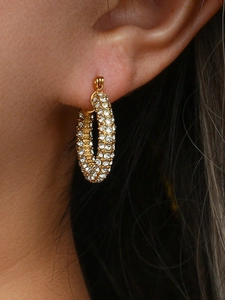 Close-up of luxury 18K gold-plated twisted hoop earrings with micro-pave crystals