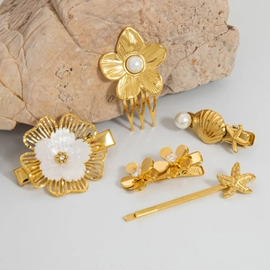 Detail of gold starfish and floral hair clips with pearls on a natural stone surface