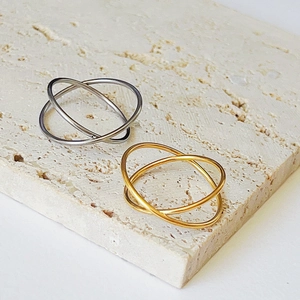 Intertwined silver and 18k gold rings on a stone surface showing smooth texture