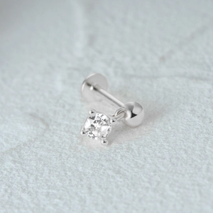 Close-up of silver cartilage stud with a small round clear gemstone pendant on textured base
