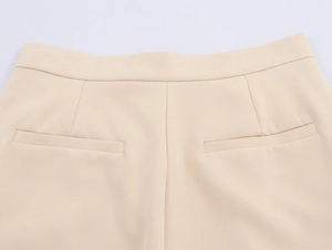 Detailed back view of beige trousers featuring waist cut and faux welt pocket design