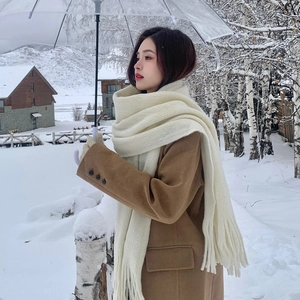 Lunga sciarpa in maglia bianco crema con frange indossata da modella sulla neve