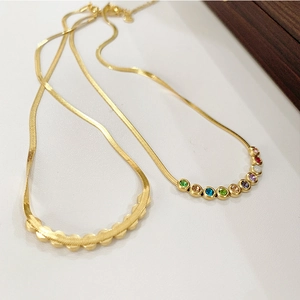 Detail of gold snake chains featuring curved pendants with colorful zircon inlay