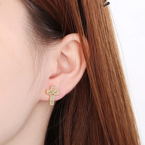 Close-up of sparkling gold cross earrings with diamonds worn by a model for a stylish look