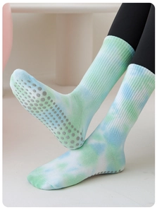 Close-up of green and blue tie-dye yoga socks with non-slip silicone grips on the sole