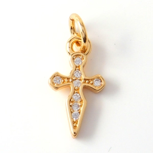 Close-up of golden metal cross pendant with sparkling crystals and jump ring
