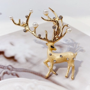 Detail of elegant gold reindeer brooch with cream matte enamel and white faux pearls