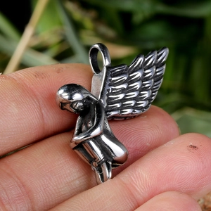 Close-up of a vintage silver angel wing pendant made of polished stainless steel