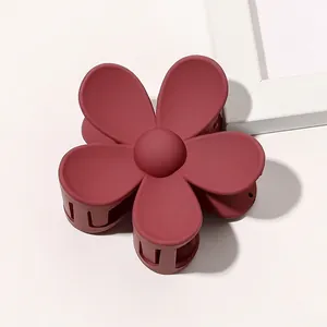 Detail of dark rose red matte flower hair claw clip with a classic five-petal floral design