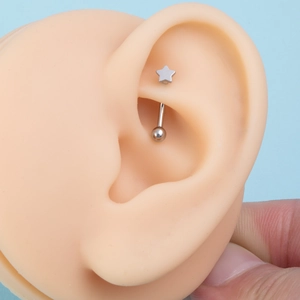 Detail shot of a star-shaped stainless steel curved barbell piercing on an ear model
