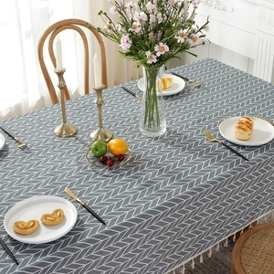 Detail of grey herringbone pattern tablecloth with white decorative tassels on the edge