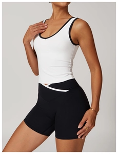Detail of white racerback sports tank with black piping and high-waist cycling shorts
