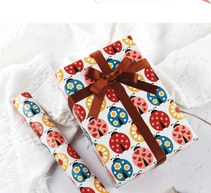 Wrapped gift box with colorful ladybug pattern paper and a dark brown ribbon bow