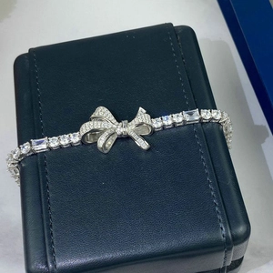 Détail d'un bracelet nœud en argent serti de zircons sur une texture en cuir noir