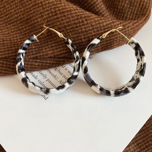 Close-up of zebra pattern hoop earrings on a knit fabric background with golden details