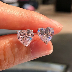 Macro view of heart-cut multi-colored zircon earrings held in hand for size detail