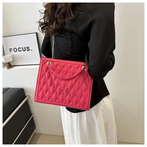 Detail of rose pink quilted crossbody bag with gold chain strap on model's shoulder