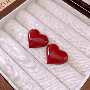 Detailed close-up of glossy red heart earrings resting in a premium wooden jewelry box