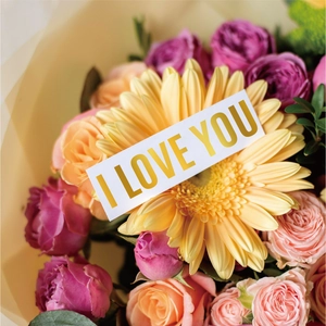Detailed close-up of a flower bouquet gift box featuring pink and orange roses with gold stickers