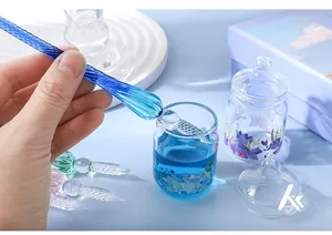 Macro detail of a spiral blue glass dip pen being dipped into a decorative ink bottle