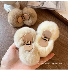 Close-up of fluffy plush hair claws in beige and brown colors held by hand
