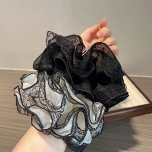 Détails de grands chouchous en dentelle noire et blanche aux volants élégants