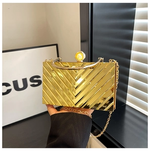 Detail of golden acrylic clutch with chevron texture, pearl clasp and metal handle