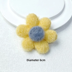 Detail showing a 6cm yellow plush flower with a dark blue center on a white pedestal