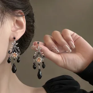 Detailed close-up of vintage tassel earrings with black beads and diamond-encrusted silver frame