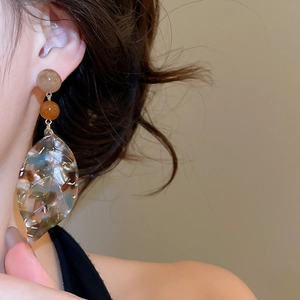 Close-up of retro acetate leaf pendant earrings with marble texture on model