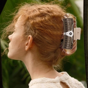 Detail of faux leather hair claw clip with bull skull motif on model in nature