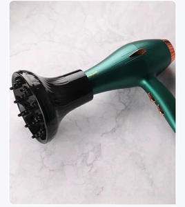 Close-up of a dark green hair dryer with a professional black diffuser on marble surface