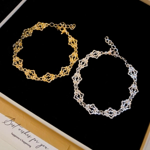 Detailed shot of hollow heart chain bracelets in gold and silver finish on black velvet
