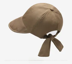 Detail view of the brown sun hat with a decorative bow on the adjustable back strap