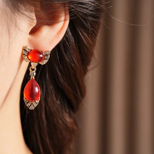 Close-up of a vintage golden earring with a red teardrop gemstone and small diamonds