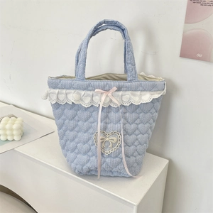 Detail of blue striped quilted bucket bag with heart embroidery and lace trim