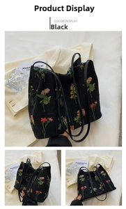 Detailed macro view of black canvas tote bag featuring vibrant floral embroidery and leather handles