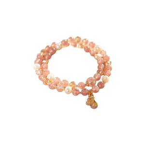 Double-layer strawberry quartz and pearl bracelet with golden bell charm on white background