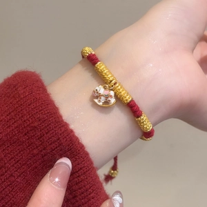 Close-up of woven red cord bracelet with a white rocking horse charm on a wrist