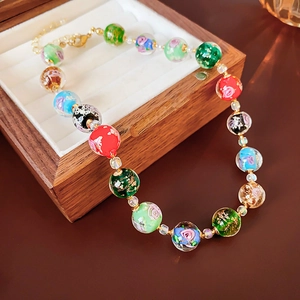 Macro shot of glass beads with floral patterns and gold leaf on a colorful necklace